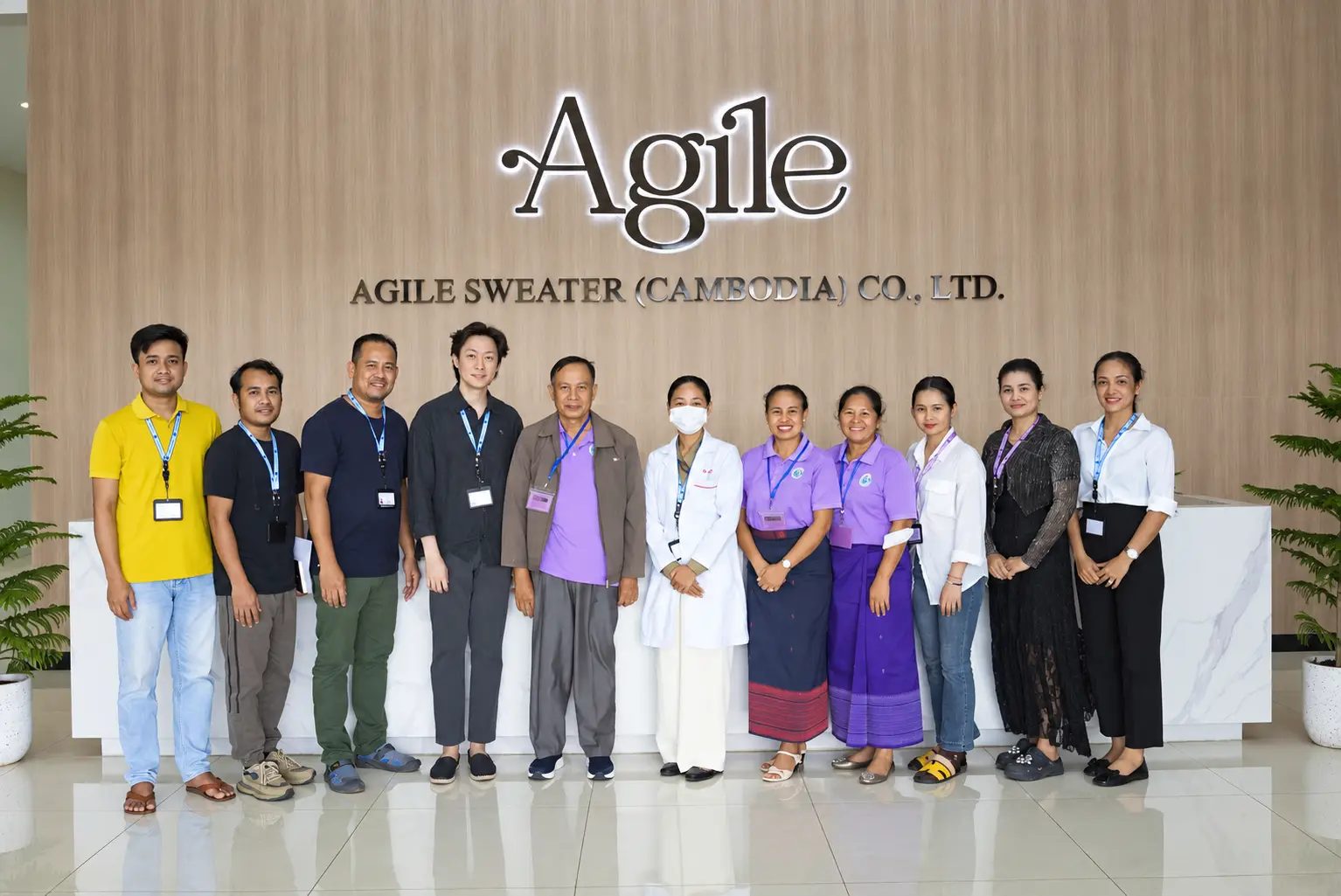 Agile Sweaterの会社ロゴ前に集まったキックオフ参加者